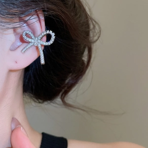Close-up of a silver bow ear cuff with pavé rhinestones worn on a model's ear