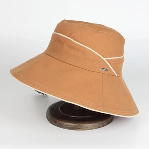 Chapeau de soleil caramel à large bord avec liseré blanc et logo sur socle en bois