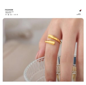 Detail of minimalist 18K gold open ring with cross design on finger with glass