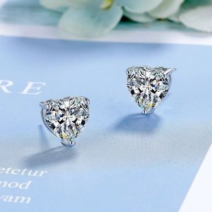 Elegant heart-cut zircon stud earrings in silver multi-prong setting on light blue card
