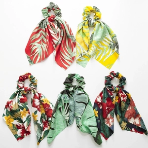 Detailed view of large satin scrunchies with vibrant tropical floral and botanical patterns