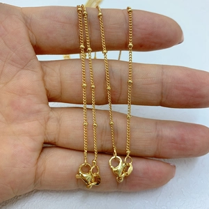 Dettaglio della catena placcata oro 18k con sfere tenuta in mano per scala