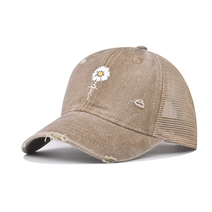 Close-up of distressed khaki baseball cap featuring embroidered daisy and mesh back