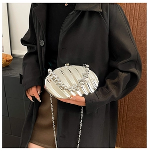 Detail of silver shell-shaped evening clutch bag with metallic texture and beaded handle