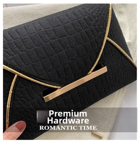 Gros plan d'une pochette noire à texture crocodile avec détails en métal doré chic