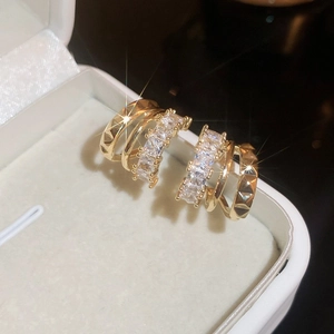 Close-up of gold C-shaped earrings with layered cubic zirconia in a jewelry box