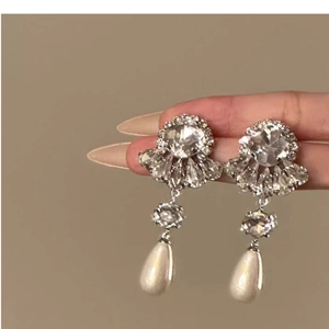 Detail of silver drop earrings with crystal flower stud and teardrop pearl pendant
