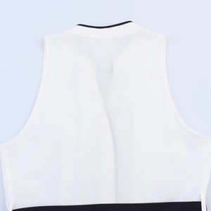 Detail van witte mouwloze jurk met zwarte contrast bies en getailleerde riemstiksels