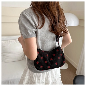 Corduroy shoulder bag with strawberry print shown on model in a cozy interior setting