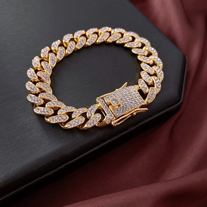 Close-up of golden rhinestone-encrusted Cuban link bracelet on a luxury black stand