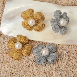 Floral stainless steel earrings with central pearl on shell and sand background