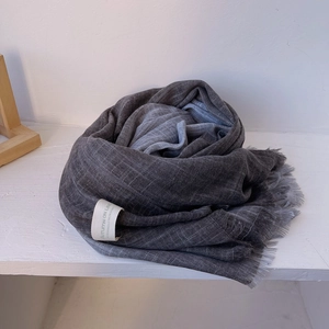 Detailed view of dark grey cotton linen scarf texture with soft fringe and logo tag