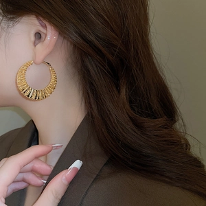 Close-up of model wearing chunky gold twisted hoop earrings with textured spiral design