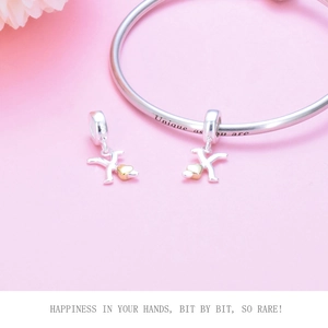 Detail of S925 silver bracelet with golden heart letter X charm on pink background