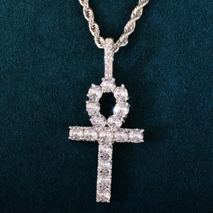 Macro view of silver Ankh cross pendant with clear cubic zirconia on dark green velvet