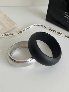 Detail shot of chunky silver polished metal and matte black resin bangle bracelets