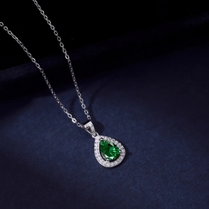 Close-up of a pear-shaped emerald green zircon pendant with sparkling white stones