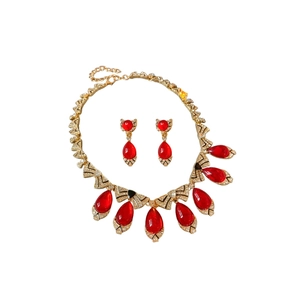 Vintage gold jewelry set with red teardrop gems and crystal bows on white background