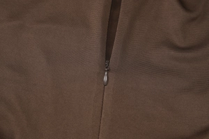 Makroaufnahme des seitlichen Reißverschlusses und der gerafften Textur am braunen Kleid