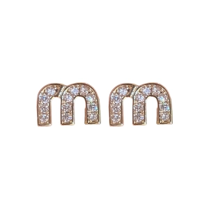 French style gold letter m earrings with zircon inlay on a clean white background