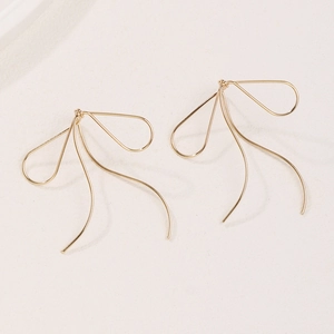 Minimalist gold wire bow earrings with a sleek French style on a beige background