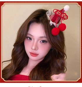 Detail of red festive hair clip featuring plush pompom and lucky character decoration