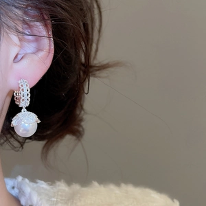 Macro shot of French vintage pearl earrings with micro-set zircons on silver hooks