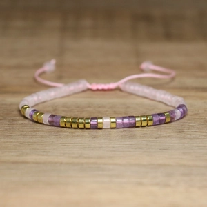 Close-up of pink and purple beaded bracelet with adjustable woven strap and gold metal spacers