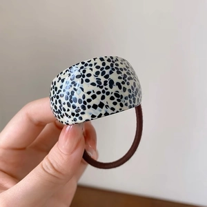 Detail of dalmatian print acetate hair tie showing the curved shell and elastic band