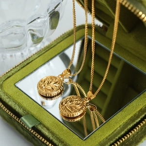 Vintage golden round floral pendant necklace on green velvet box with reflection