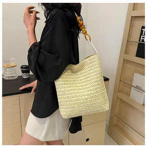 Detail of hand-woven straw bag featuring decorative white beads and natural wood accents