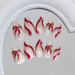 Faux ongles amande avec paillettes blanc nacré, rubans rouges et rayures ondulées