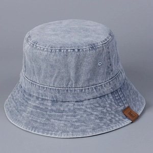 Detail of vintage washed denim bucket hat featuring stitching and a brown leather logo tag