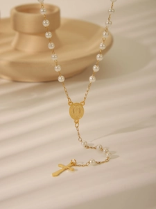 Detail of elegant gold cross pendant necklace with white pearls and Virgin Mary medal