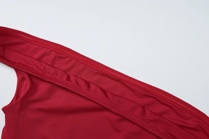 Détail de la couture d'une robe en maille rouge montrant la texture du tissu fin