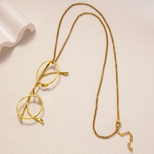 Detailed macro of gold metal glasses pendant with lobster clasp and cross chain