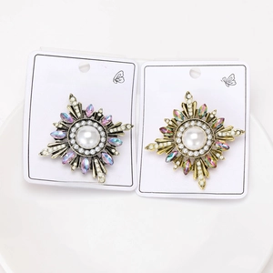Detail view of two vintage baroque sunburst brooches with pearls and colorful rhinestones