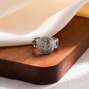 Macro view of vintage Saint Benedict medal ring on walnut wood and silk background