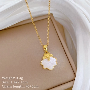 Dettaglio di una collana a conchiglia dorata con ciondolo a stella marina su sfondo beige