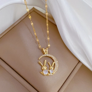 Detail of luxury gold crescent moon pendant with micro-pave rabbits on a wave chain