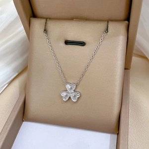 Macro shot of silver clover pendant with engraved texture in a luxury gift box