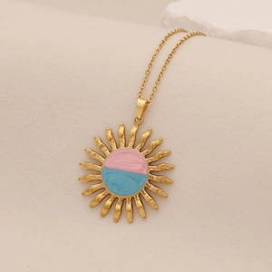 Golden sunflower necklace with blue and pink pendant on beige textured background
