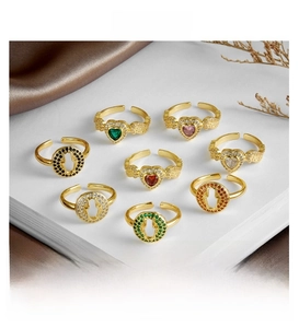 Close-up of gold-plated open rings with colorful zircon in heart and Hamsa Hand designs