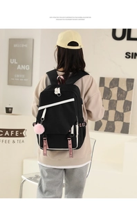 Detailed back view of a black student backpack with sport strap and plush ball charm