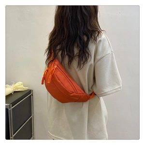 Orange leisure chest bag showing woven zipper pulls on a model wearing an oversized tee