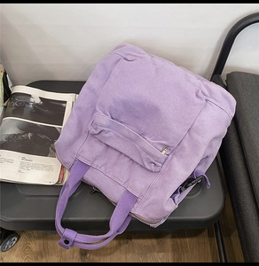 Close-up of a purple canvas backpack featuring a front pocket and soft washed texture
