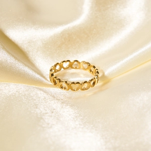 Macro shot of gold-plated hollow heart ring on champagne silk fabric background