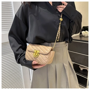 Detail of beige quilted crossbody bag with gold chain strap and circular twist lock