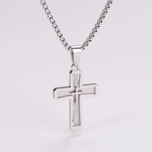 Detail showing a layered silver cross pendant with a box chain on a clean white background