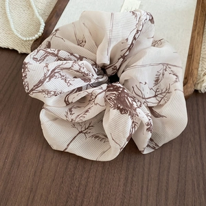 Detail of vintage cream scrunchie with brown floral pattern on rustic wood background